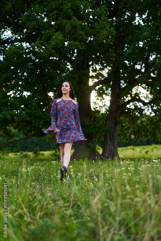 Woman in floral dress standing in summer meadow.........