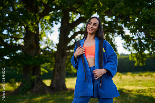 Woman in martial arts gi standing in nature