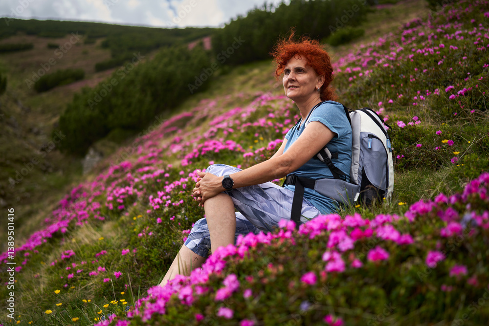 Woman resting in alpine rhododendron meadow during summer hike.........