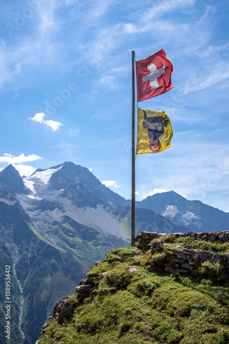 Swiss flag an flag of canton uri waving in the wind at a mountain hut in Switzerland