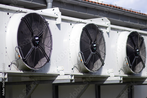 Dry cooler unit mounted on the exterior wall of a building. Industrial silver-gray equipment with metal casing, captured on a neutral concrete background. Ventilation and cooling system detail.

