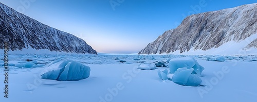A frozen landscape with icebergs and mountainous slopes under blue skies