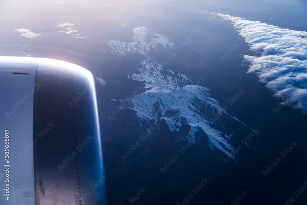 Airplane turbine against the backdrop of distant mountains below, seen from the cabin window