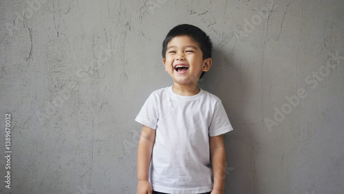 Obraz na płótnie A young boy standing in front of a gray wall, ideal for use in editorial or advertising content w salonie