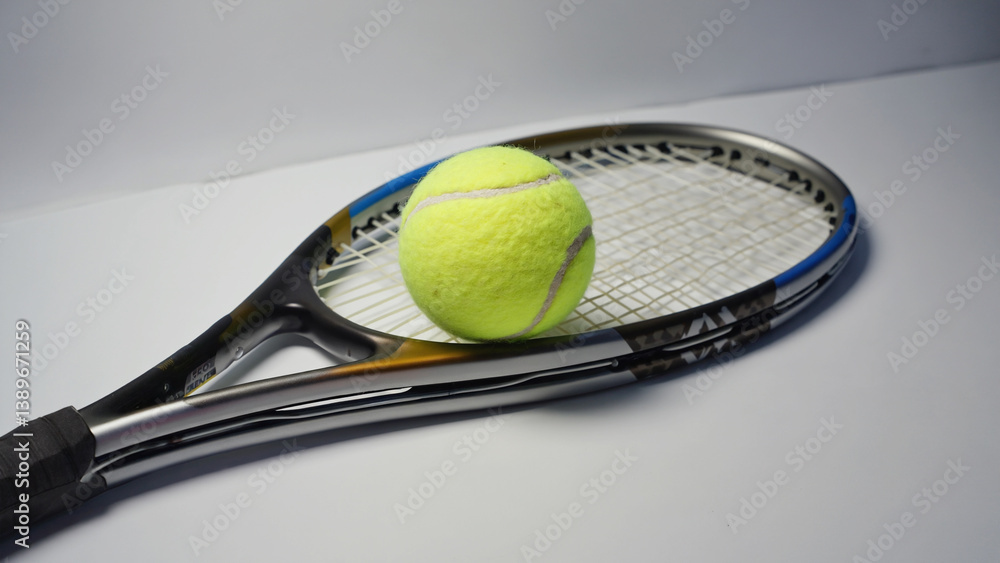 A tennis racket with a tennis ball resting on its strings, ideal for illustrations about sports or recreation