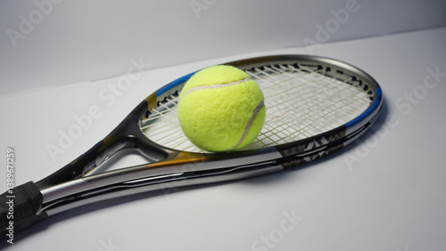 Obraz na płótnie A tennis racket with a tennis ball resting on its strings, ideal for illustrations about sports or recreation w salonie