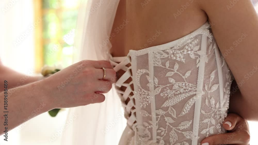 The bride is having her wedding dress laced up in the morning. The bride is having her wedding dress laced up in the morning.