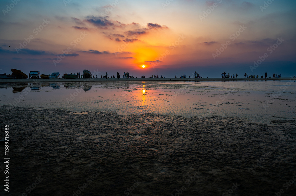 Fototapeta premium Sunset at Colva Goa beach in South India, silhouette of boats and people, tropical west coast, Arabian Sea in Asia, vacation destination