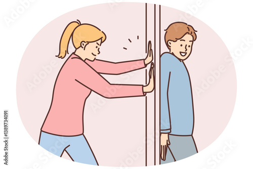 Positive man hides behind door preventing girlfriend from passing or arranging prank