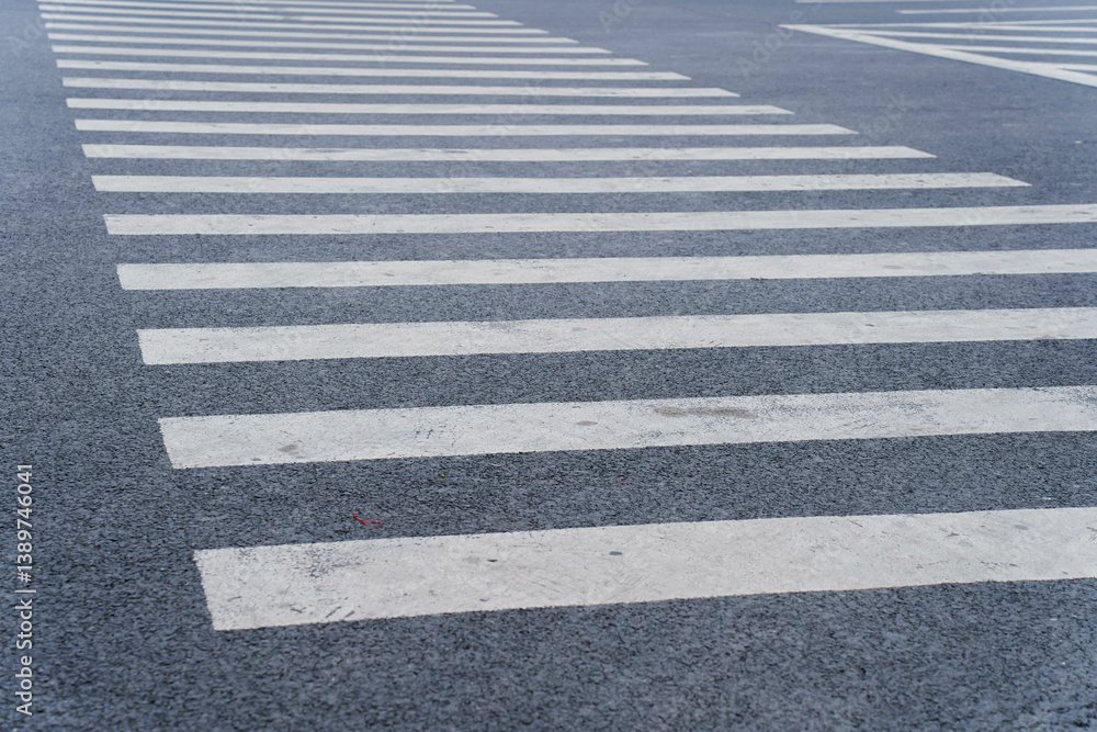 Empty crosswalk on a city street with striped white lines, indicating pedestrian crossing area. Concept of urban infrastructure, pedestrian safety, and road design. High quality photo