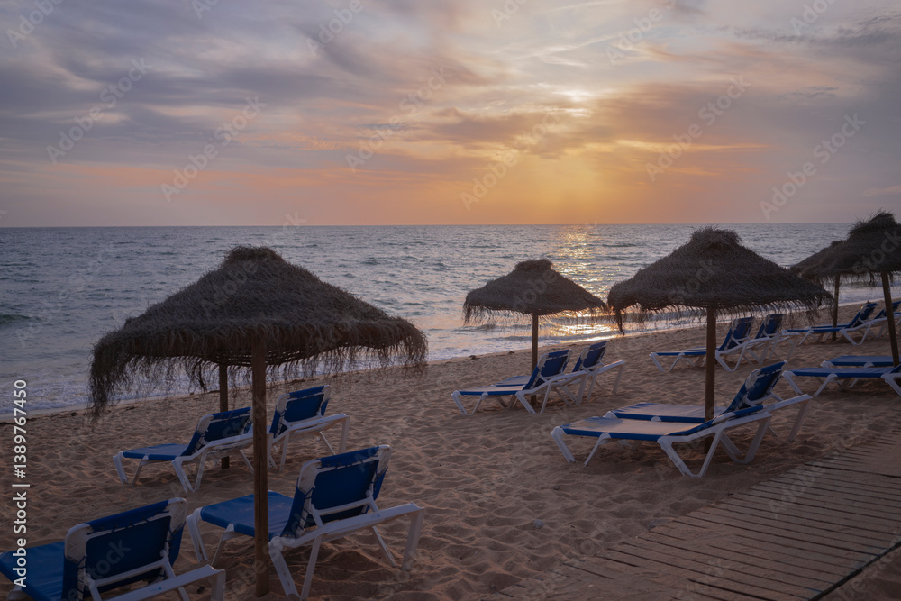 Sunset on the beach with sunbeds and umbrellas