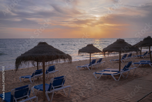 Obraz na płótnie Sunset on the beach with sunbeds and umbrellas w salonie