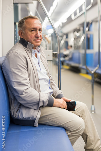 Positive elderly man sitting in an empty subway carriage while train is moving