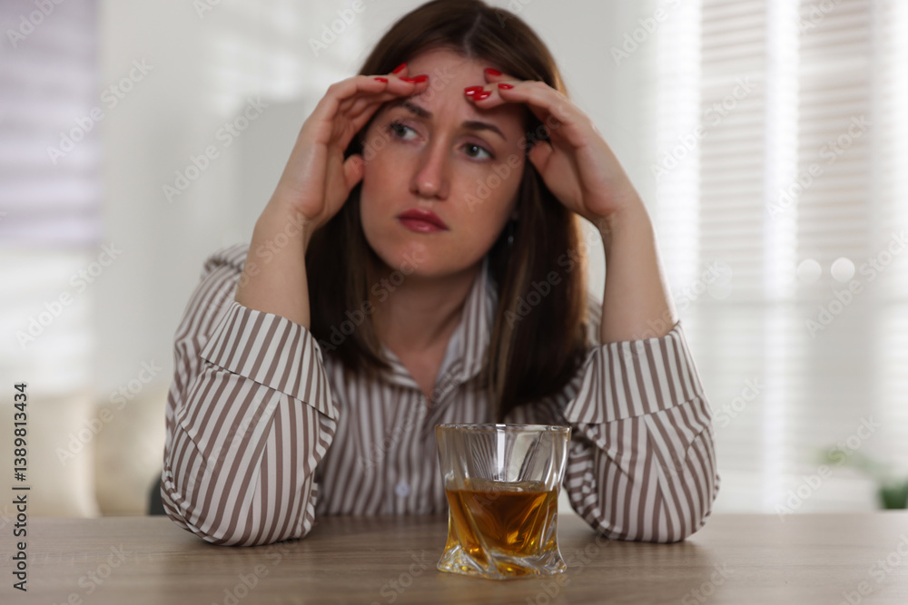Alcohol addiction. Woman at wooden table with glass of whiskey indoors, selective focus Alcohol addiction. Woman at wooden table with glass of whiskey indoors, selective focus