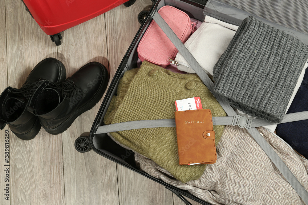 Fototapeta premium Passport with ticket on packed suitcase indoors, top view