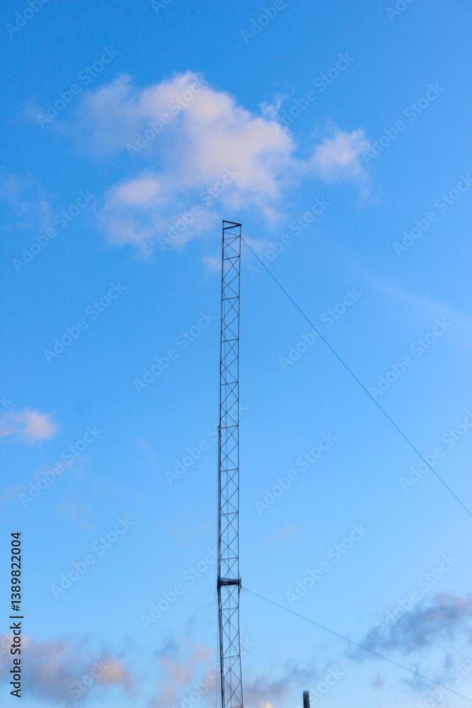 Tall communication tower against a mostly clear blue sky with a few wispy clouds. Tall communication tower against a mostly clear blue sky with a few wispy clouds.