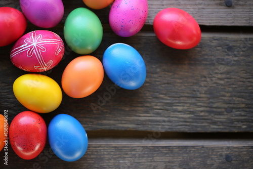 The Easter colorful eggs are lying on the wooden table. One egg is traditionally decorated.