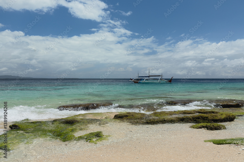 A small traditional fishing boat at the coast of Morotai island, North Maluku district, during bright sunny day A small traditional fishing boat at the coast of Morotai island, North Maluku district, during bright sunny day
