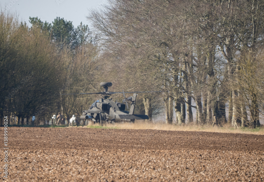 British army AH-64E Boeing Apache Attack helicopter gunship (ZM735 ArmyAirCorp) taking off from inside a woodland copse