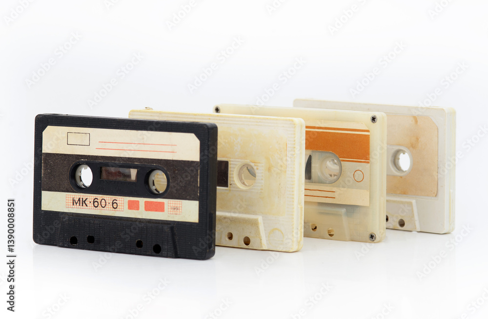 Obraz premium A row of vintage cassette tapes with faded labels on a white background, evoking retro audio nostalgia.