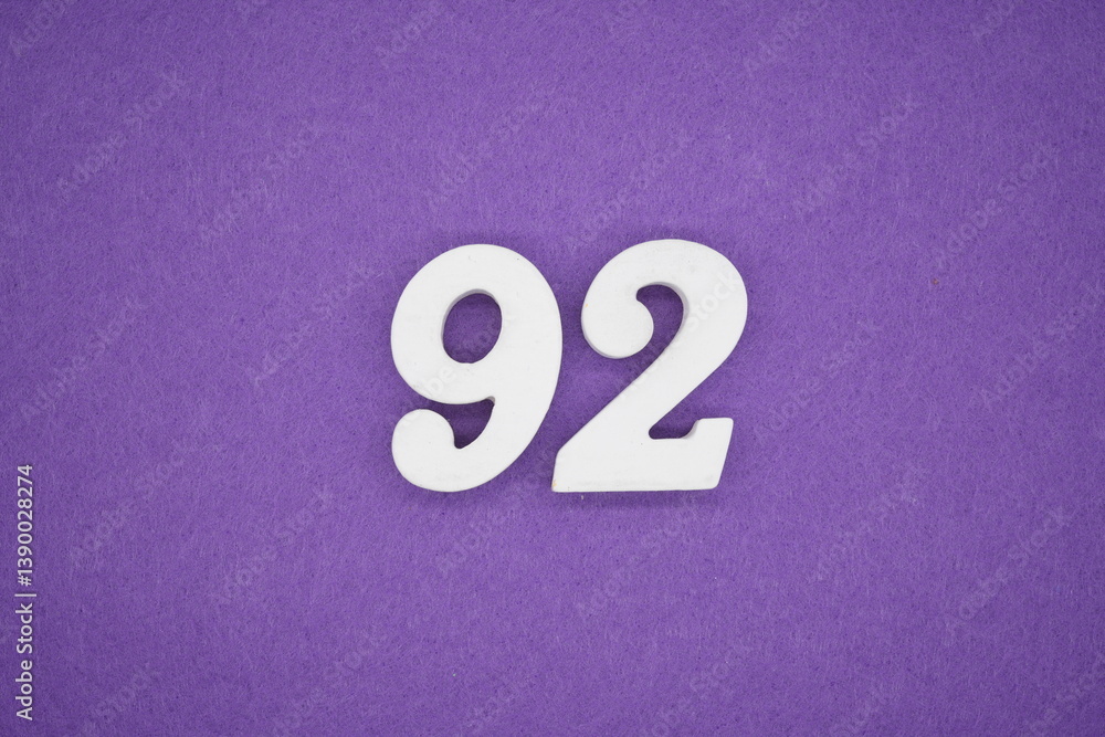 The numbers are made of white painted wood placed on a purple paper background. The numbers are made of white painted wood placed on a purple paper background.