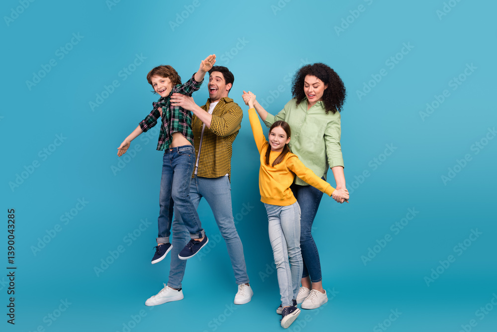 Fototapeta premium Happy young family enjoying quality time together in casual attire against a blue background with laughter and bonding moments