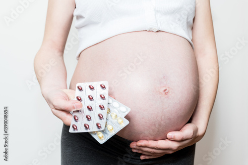pregnancy belly, pregnant woman and a set of pregnancy vitamins
