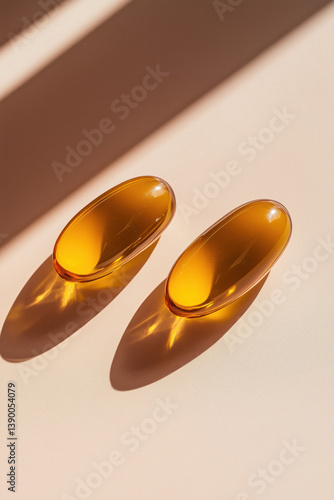 Obraz na płótnie Two golden omega-3 fish oil capsules lie on a beige surface with soft shadows. w salonie