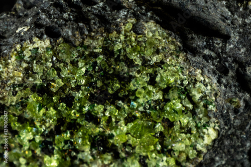 Close-up of gem quality small vibrant green peridot crystals with a few dark Olivine crystal