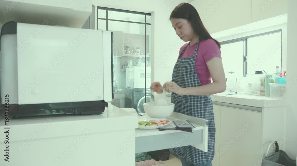 A woman cooks in a modern kitchen, preparing fresh ingredients for a meal. The bright and organized space highlights a commitment to home cooking and healthy eating. A woman cooks in a modern kitchen, preparing fresh ingredients for a meal. The bright and organized space highlights a commitment to home cooking and healthy eating.