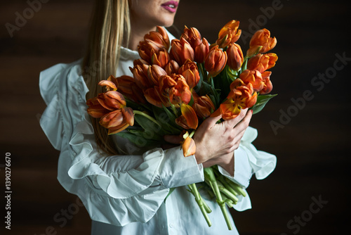 Woman Holding Lush Bouquet of Orange Tulips, Embracing Vibrant Spring Blooms, Close-up, Floral Arrangement, Elegance, Nature Appreciation Concept