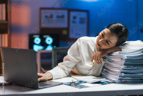 Cuadro en lienzo Tired doctor resting her head on a stack of documents while using a laptop, work