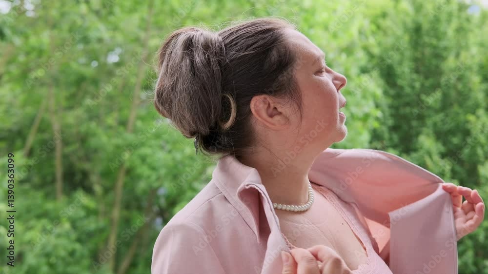 mature woman, 55, elegantly dressed in pink feeling unwell, fans herself, experiencing hot flashes and discomfort from menopause, feminine health issues, aging gracefully mature woman, 55, elegantly dressed in pink feeling unwell, fans herself, experiencing hot flashes and discomfort from menopause, feminine health issues, aging gracefully
