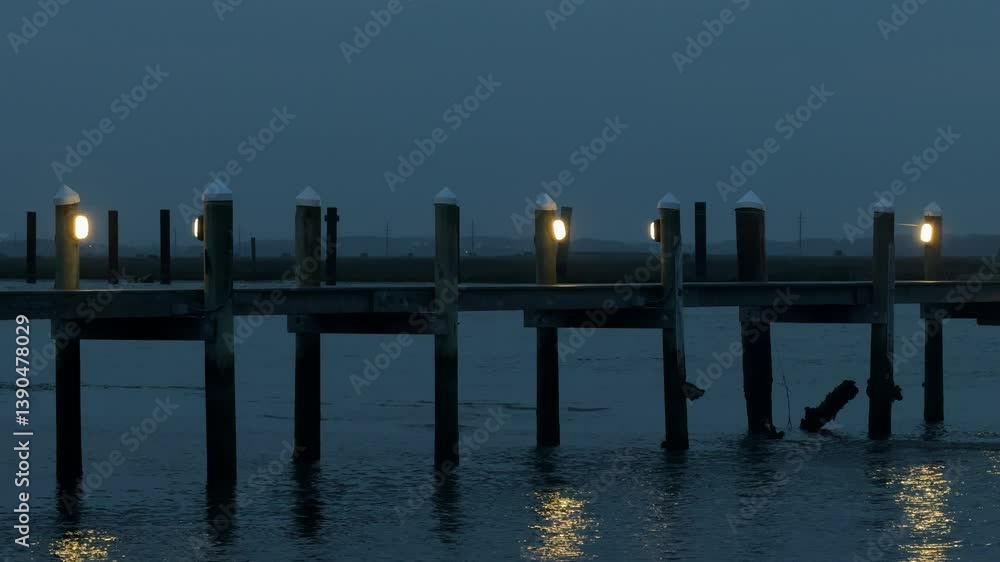 dark evening light with dock over the water with lights and water lapping underneath dark evening light with dock over the water with lights and water lapping underneath