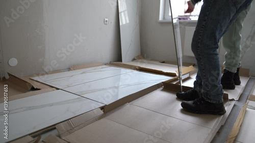 The craftsmen lay out the tiles to fit the pattern. Laying large-format porcelain tiles measuring 120 by 60 on the walls. High quality 4k footage