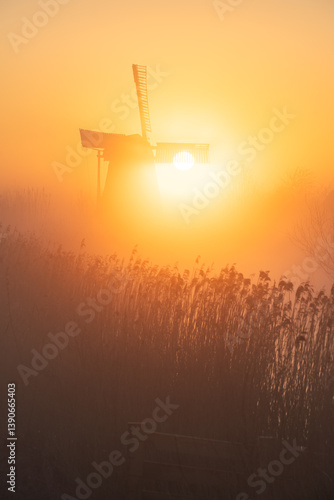 Obraz na płótnie Sunrise at a Dutch, traditional windmill and a canal in the spring fog. w salonie