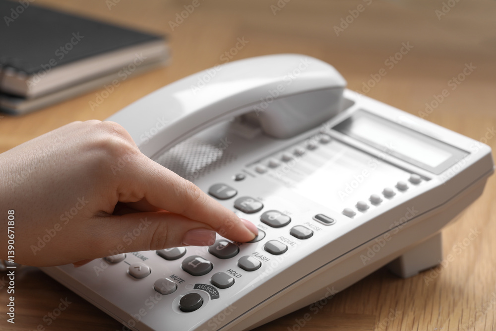 Woman dialing number on telephone at wooden table, closeup Woman dialing number on telephone at wooden table, closeup