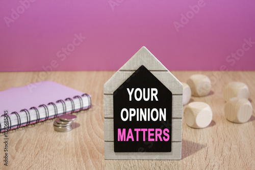 Text Your opinion matters on a black board. Beautiful purple background. Notebook and silver coins on the table. Business concept.