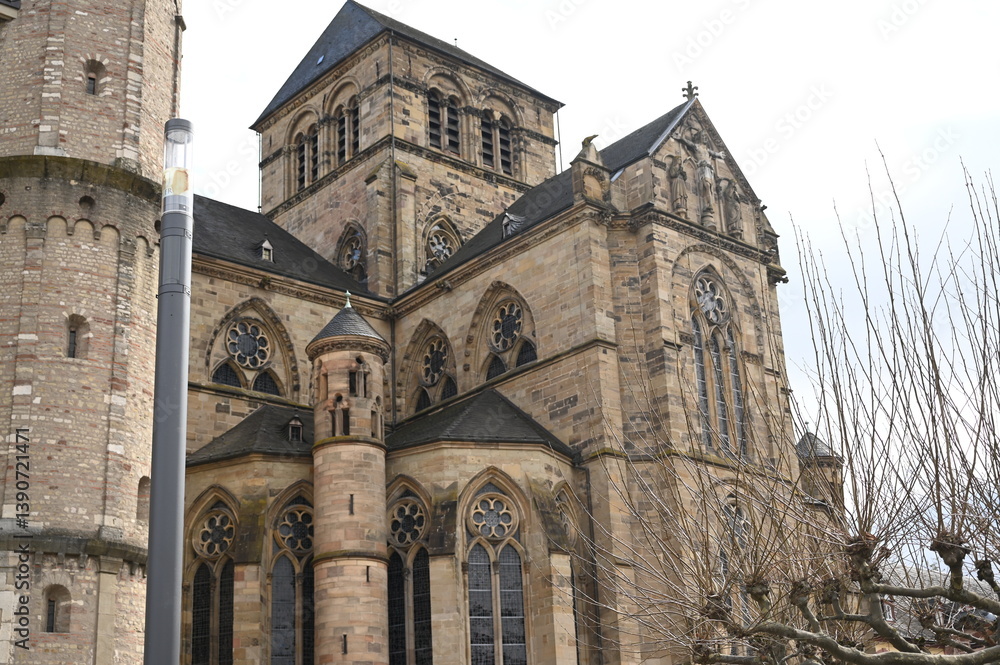 Fototapeta premium Gothic cathedral facade with tall stained glass windows and stone architecture. Historical European church building, detail of wall and arches. Travel and heritage concept.