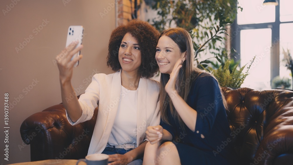 Obraz premium Two women on video call with friends while sitting in cozy coffee shop