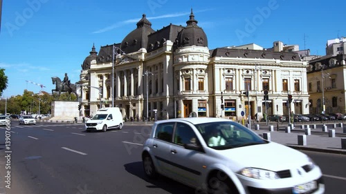 Bucharest, Romania - CIRCA October, 2017: Traffic in Bucharest on Calea Victoriei Avenue in front of National Library building and Statue of King Carol I. Cars are moving along the Victory Avenue