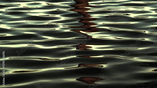 Ripples on the water with reflections in dramatic tones. Dramatic reflection of sunset in the water.