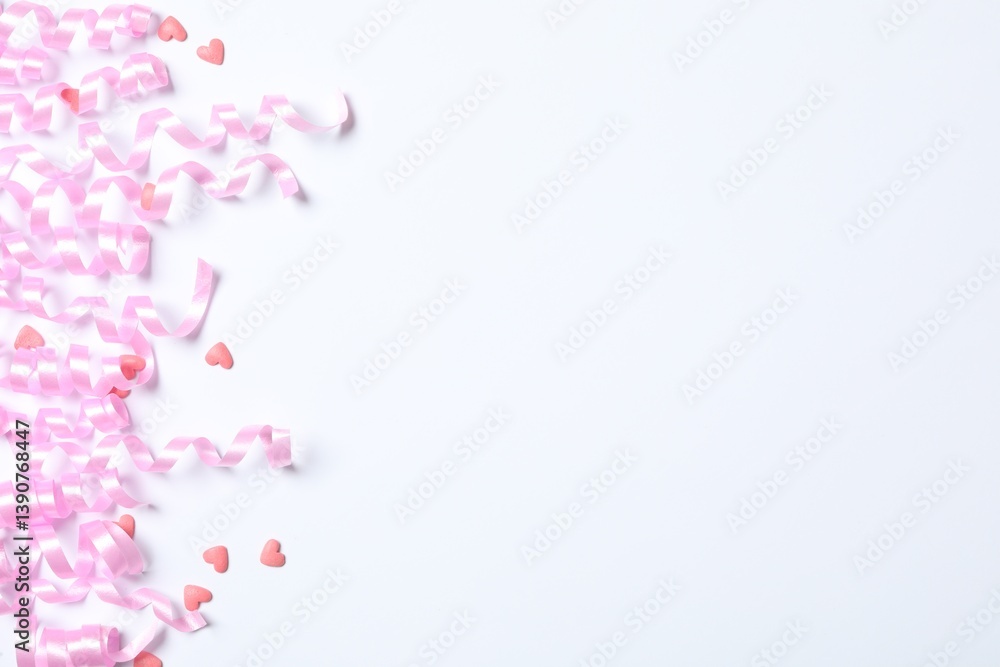 Pink serpentine streamers and heart shaped confetti on white background, top view Pink serpentine streamers and heart shaped confetti on white background, top view