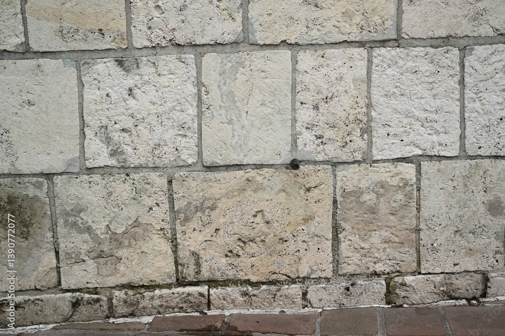 Naklejka premium Natural stone wall texture with rectangular beige and gray blocks. Rough surface and organic patterns ideal for architectural backgrounds and design materials.