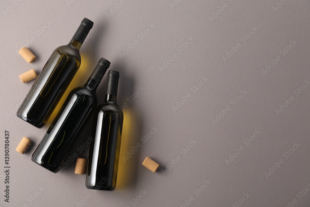 Naklejka premium Bottles of wine and corks on grey background, flat lay. Space for text
