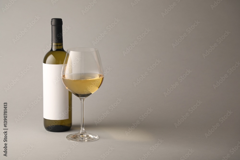 Tasty white wine in glass and bottle on light grey background, space for text Tasty white wine in glass and bottle on light grey background, space for text