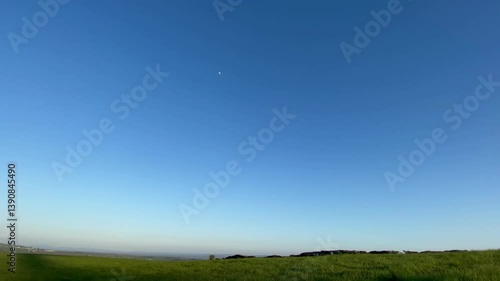Wind turbine spinning at sunset in rural field
A modern wind turbine rotates slowly at sunset in green field. Captured in spring with clear skies, it highlights sustainable energy and natural beauty.