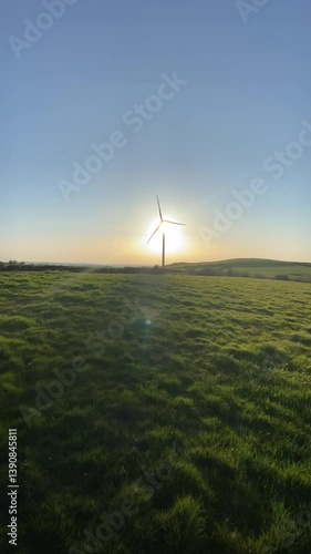 Wind turbine slowly spinning during sunset. Captures the contrast between technology and nature, highlighting renewable energy in golden light.