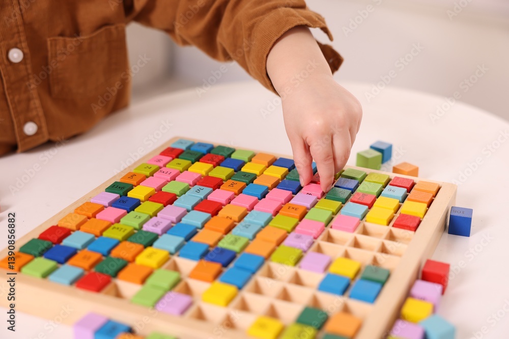 Fototapeta premium Motor skills development. Little boy playing with Times table tray indoors, closeup