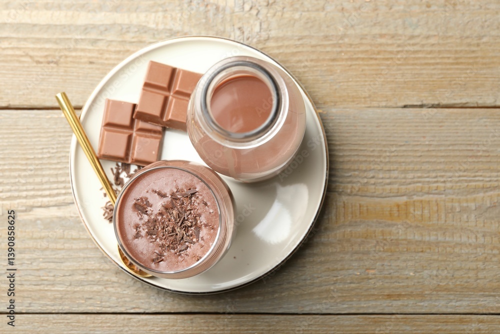 Tasty chocolate milk with shavings and pieces on wooden table, top view Tasty chocolate milk with shavings and pieces on wooden table, top view